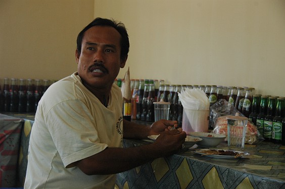 Ein Lastwagenfahrer verzehrt in seiner Mittagspause einen Teller Sate kambing mit Reis  und plauscht mit  anderen Gästen.